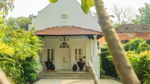 A white building with a tiled roof, a pool, and large vases on the porch. - ELIVAAS Maison 10 Luxe 4 BHK Villa  (Siolim)