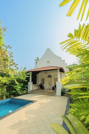 Edifício branco com telhado em cerâmica e piscina em primeiro plano.