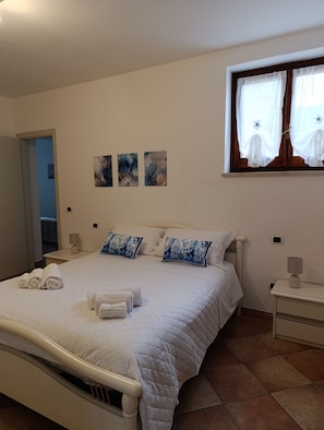 Un lit bien fait, avec des oreillers, une table de chevet avec une lampe et des œuvres d’art accrochées au mur.