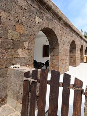 A stone archway leading to a room with a window and a door.