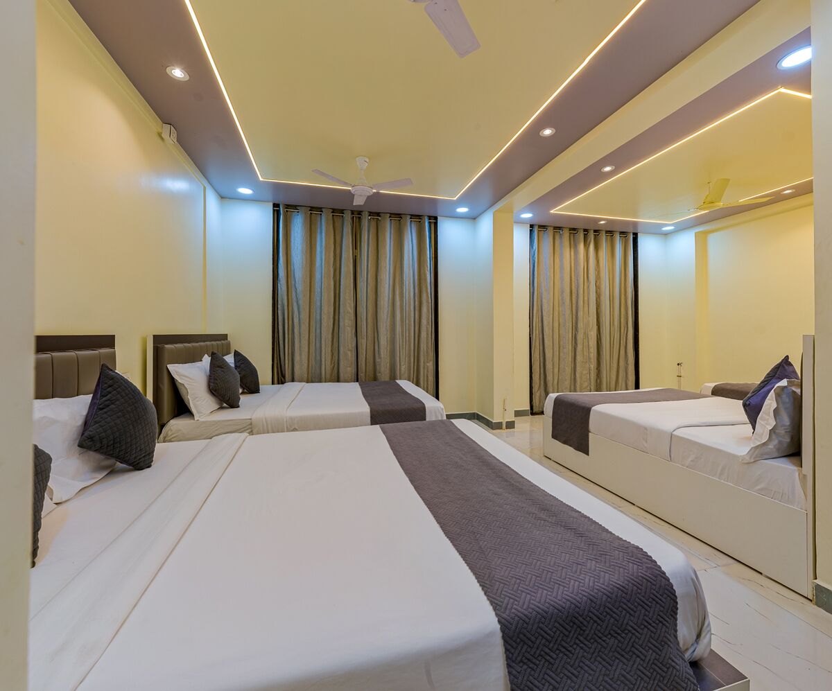 A hotel room with three beds, a ceiling fan, and a large mirror.