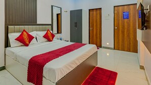 Ein modernes Hotelzimmer mit Bett, Deckenventilator, Spiegel, Kleiderschrank und Fernseher.