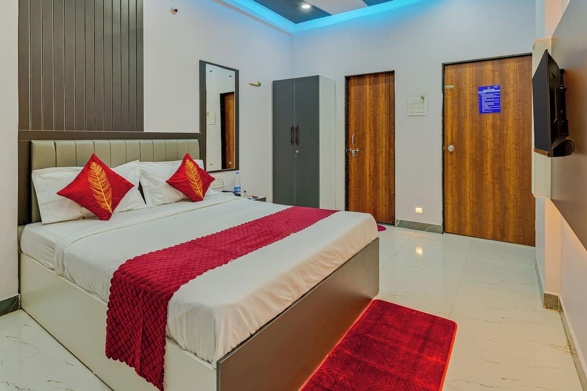 A modern hotel room with a bed, a wardrobe, a mirror, a ceiling fan, and a television.
