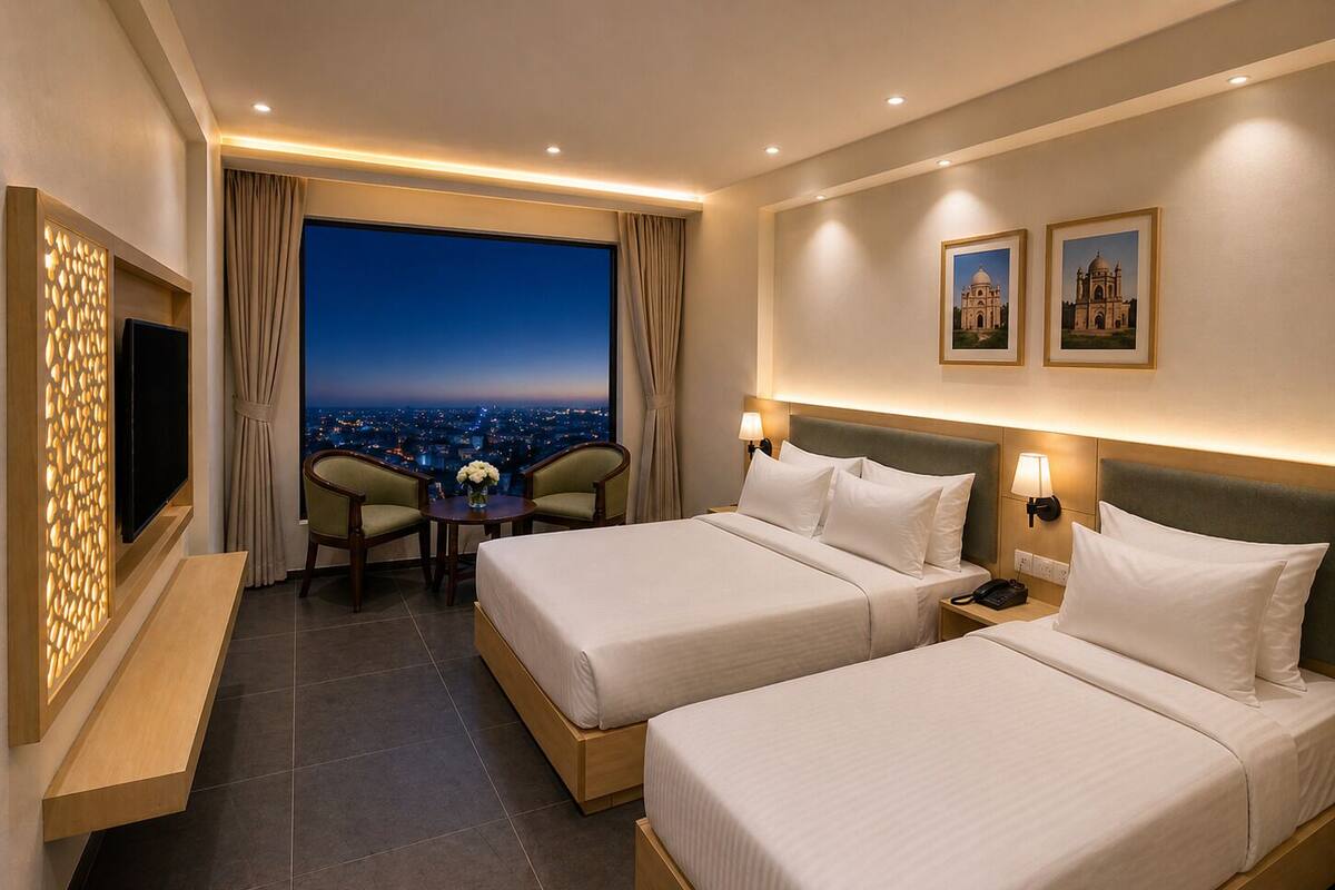 Une chambre d’hôtel avec deux lits, une télévision, une petite table avec des chaises et une vue sur la ville.