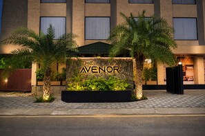 A hotel entrance with a sign that reads 'THE AVENOR' and a landscaped area with palm trees. - The Avenor - Luxury Hotel in Jaipur (Jaipur)
