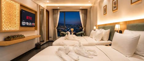A hotel room with two beds, a TV, a city view, and a wooden shelf with decorative items.