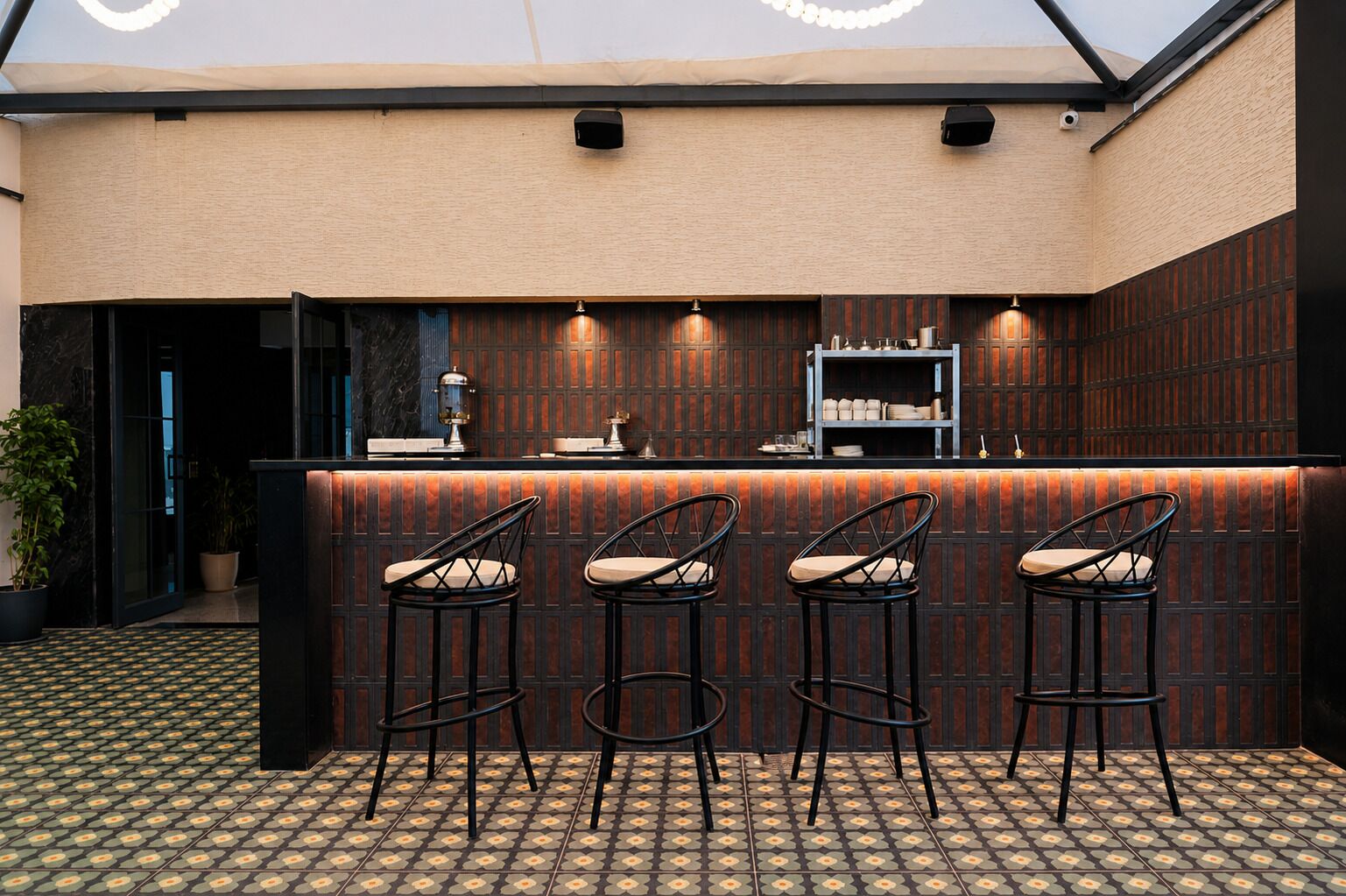 Una zona de bar con mostrador, tres taburetes y suelo estampado.