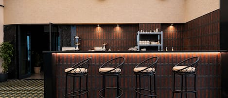 A bar area with a counter, three bar stools, and a patterned floor.