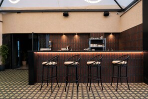 A bar area with a counter, three bar stools, and a patterned floor. - The Avenor - Luxury Hotel in Jaipur (Jaipur)