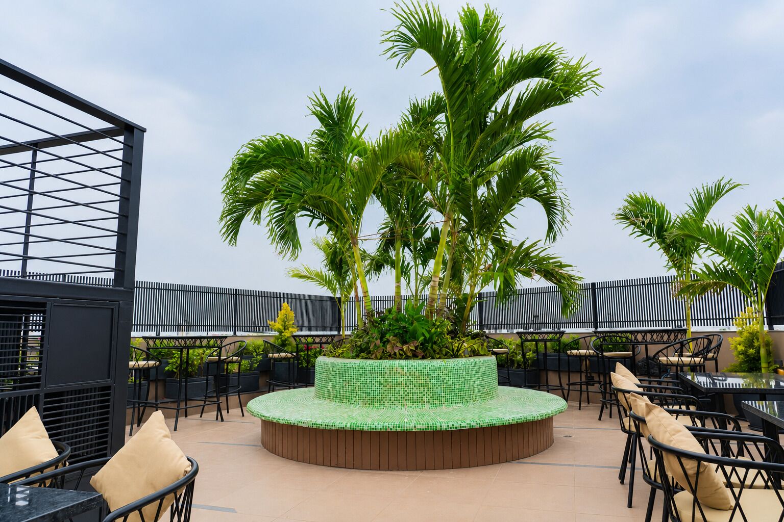 A rooftop terrace with a circular seating area, palm trees, and outdoor furniture.