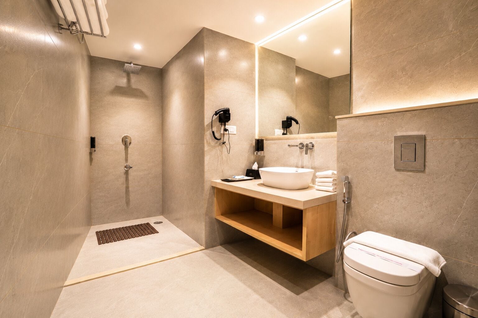 A modern bathroom with a walk-in shower, a vanity with a large mirror, and a toilet.