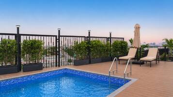 Piscina en la azotea con sillones de descanso y plantas en macetas.