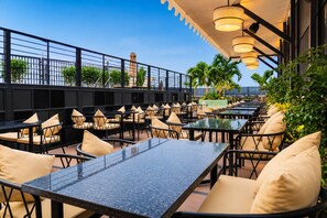 Un espace extérieur aménagé avec des tables et des chaises, une rambarde et une vue sur la mer.