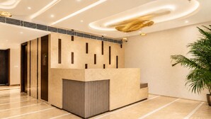 A reception area with a modern design, featuring a reception desk, a potted plant, and a ceiling with recessed lighting. - The Avenor - Luxury Hotel in Jaipur (Jaipur)