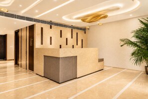 A reception area with a modern design, featuring a reception desk, a potted plant, and a ceiling with recessed lighting. - The Avenor - Luxury Hotel in Jaipur (Jaipur)
