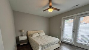 A bedroom with a bed, nightstand, ceiling fan, and a sliding glass door. - Entire home ,Clean, quiet, and cozy—everything you need for the perfect stay (Virginia Beach)