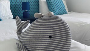 Ein Bett mit einem gestreiften Kopfkissen, einer blauen Lampe und gemusterten Kissen an einem blauen Kopfteil.