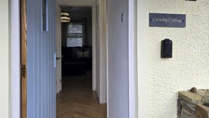 Ein Flur mit einer Holztür, einem Schild mit der Aufschrift 'Cowslip Cottage' und einer Steinmauer.