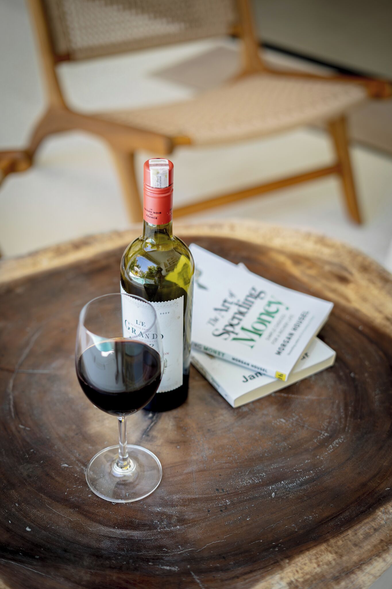 Een fles wijn en een glas op een houten tafel, met een boek ernaast.