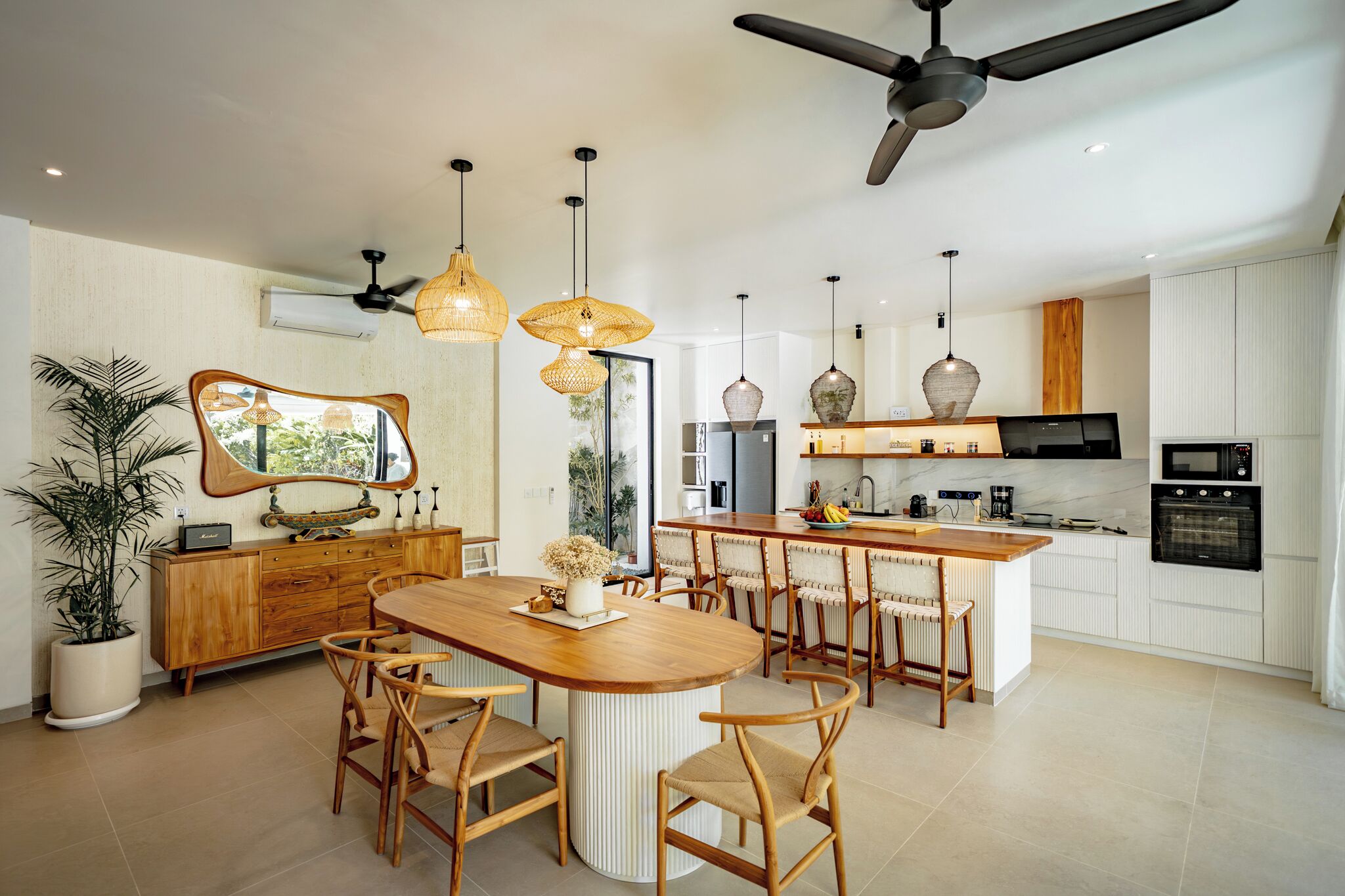 A modern kitchen with a central island, pendant lighting, and a ceiling fan.