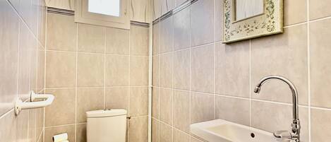 A bathroom with a toilet, sink, and a window.