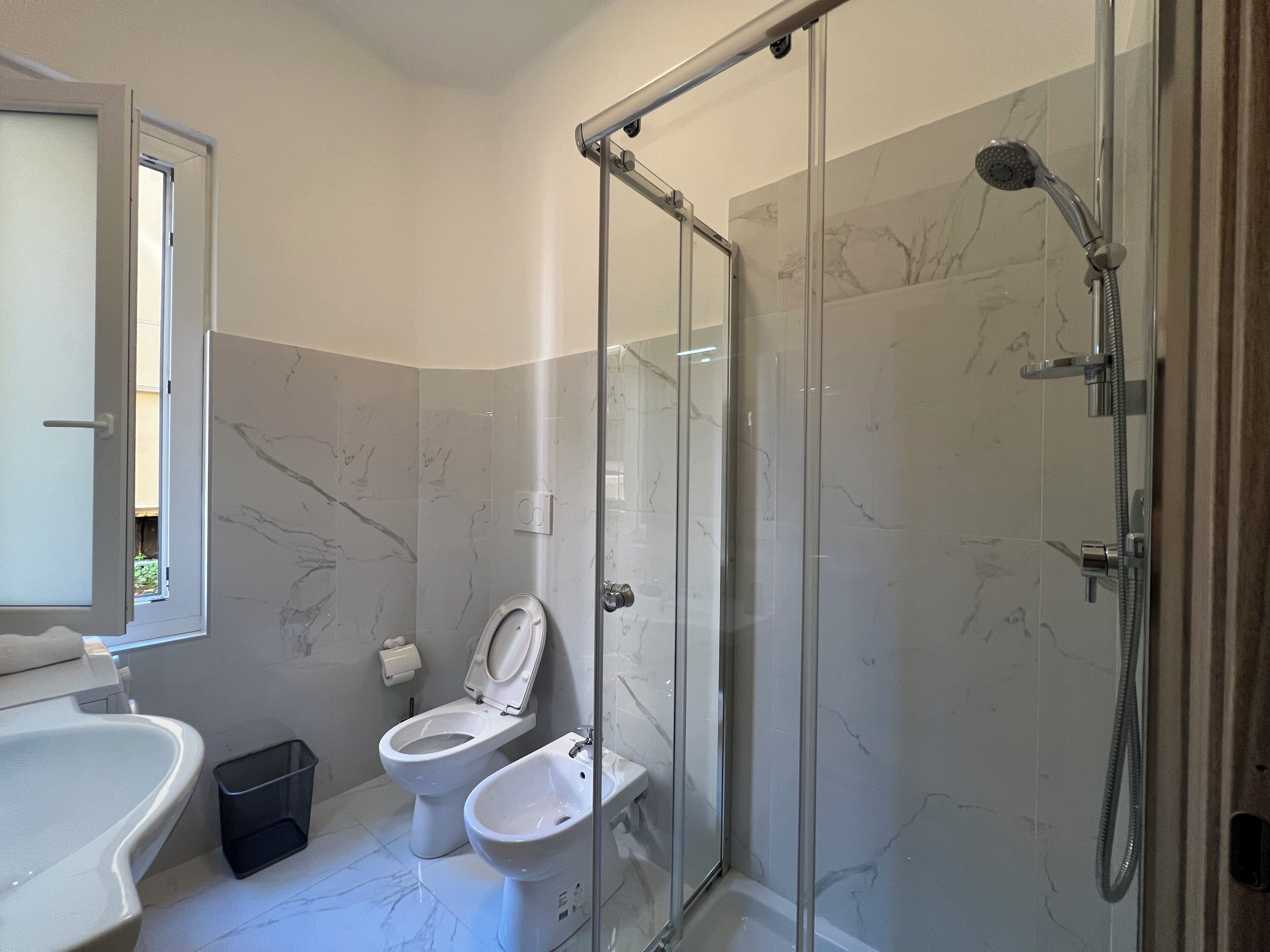 Une salle de bain moderne dotée d’une douche à parois de verre, de toilettes et d’un bidet.