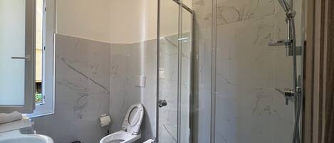 Une salle de bain moderne dotée d’une douche à parois de verre, de toilettes et d’un bidet.