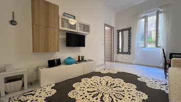 Un salon moderne doté d’un téléviseur à écran plat, de meubles en bois, d’un miroir décoratif et d’un tapis à motifs.