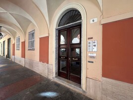 Un corridoio con soffitti a volta, una porta con pannelli di vetro e una insegna che indica la stanza numero 6.