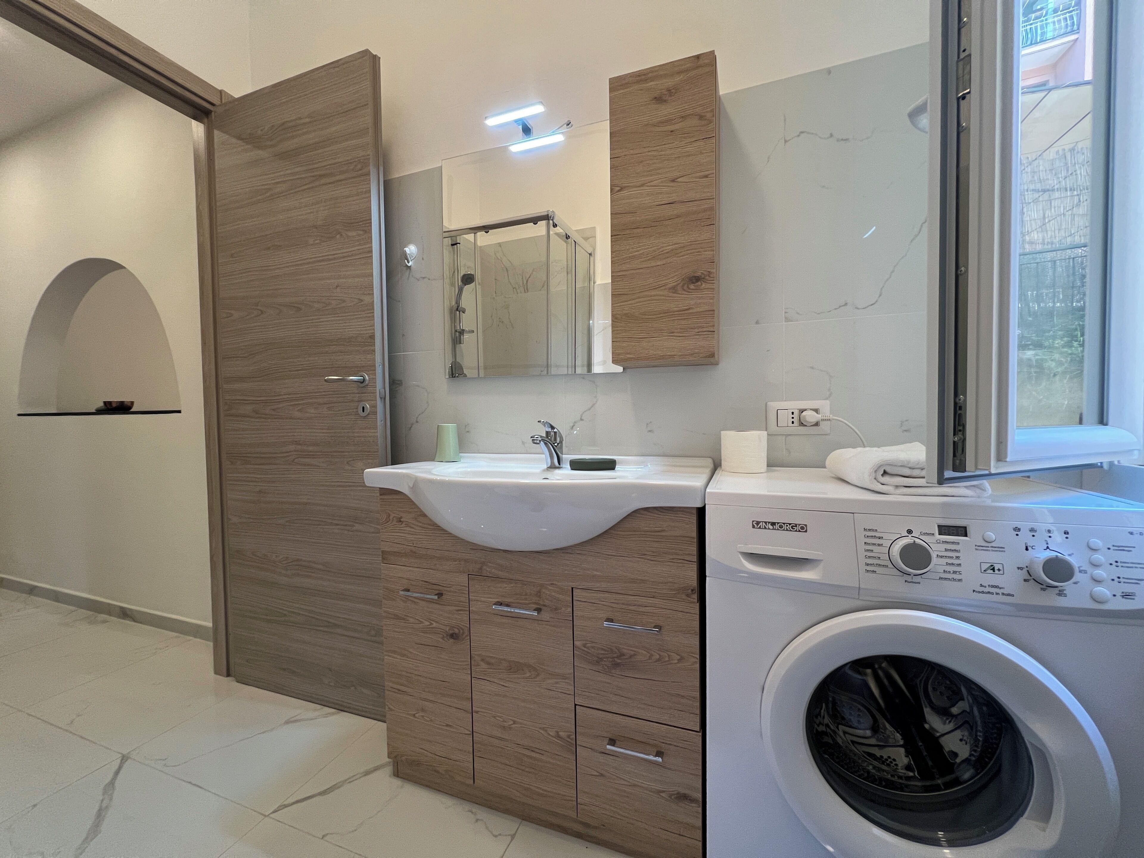 A modern bathroom with a built-in washing machine, a vanity with a sink, and a mirror.