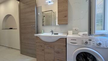A modern bathroom with a built-in washing machine, a vanity with a sink, and a mirror.