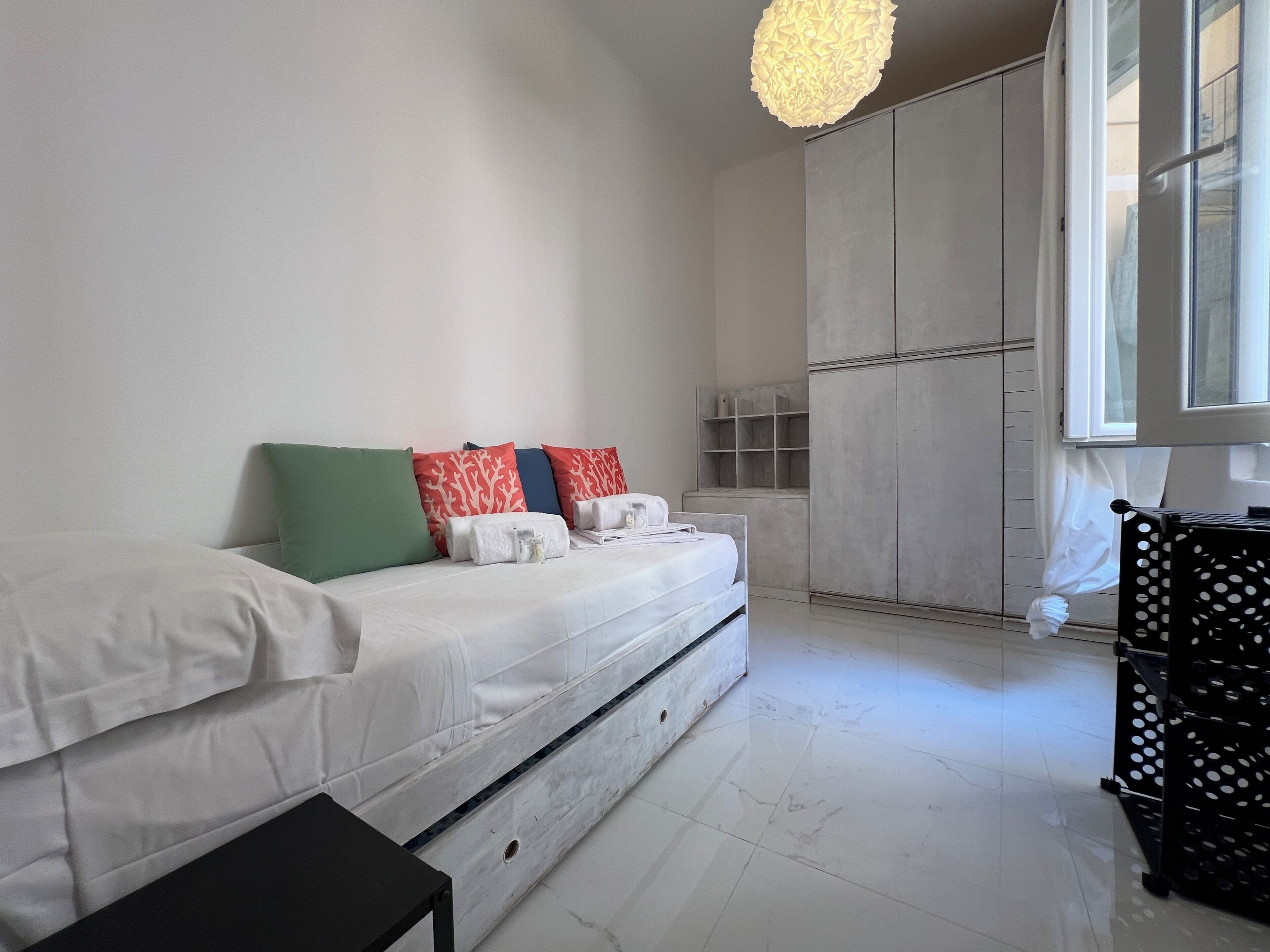 A modern bedroom with a bed, pillows, a wardrobe, and a window.