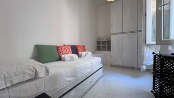 A modern bedroom with a bed, pillows, a wardrobe, and a window.