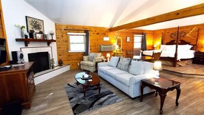 Ein gemütliches Blockhaus-Interieur mit Kamin, einer Couch, einem Fernseher und einem Bett.