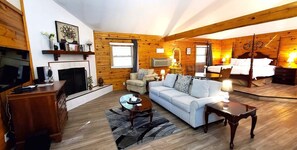 A cozy log cabin interior with a fireplace, a sofa, a television, and a bed.