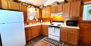 A kitchen with wooden cabinets, a white refrigerator, a stove, and a microwave.