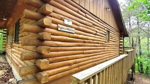 Eine Blockhütte mit Holzfassade, einem Schild mit der Aufschrift 'Nights in White Satin' und einer Holzterrasse.