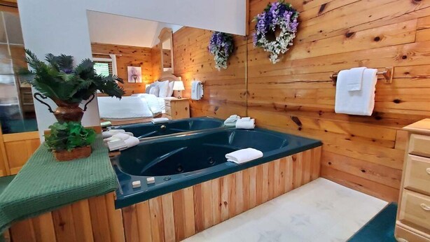Een spa-ruimte met houten wanden, twee whirlpools, een houten dressoir en een spiegel.