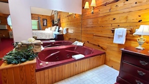 A wooden interior with a large bathtub, a mirror, and a wooden dresser with drawers. - Intimate Log Cabin #2 at Wisteria (Eureka Springs)