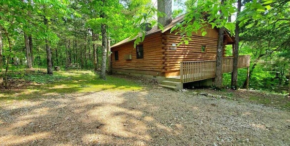 Une cabane en bois dotée d’une terrasse, entourée d’arbres.