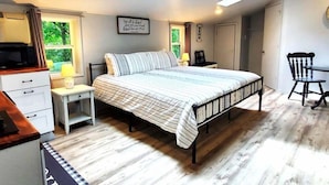 A bedroom with a bed, bedside tables, a desk, a chair, a ceiling fan, and a skylight. - Secluded Farm House at Wisteria (Eureka Springs)