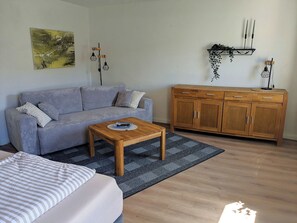 Una sala de estar con un sofá, una mesa de centro, un mueble y un cuadro en la pared.