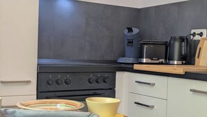 A modern kitchen with a built-in stove, a coffee maker, and a kettle on the countertop. - Holiday apartment Collis in our guesthouse in the old town of Zell (Moselle) (Zell (Mosel))