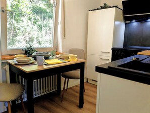 Una cocina con una mesa de comedor, sillas, estufa y ventana con vistas a árboles.