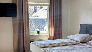 A bedroom with a bed, curtains, a window, and a radiator. - Holiday apartment Collis in our guesthouse in the old town of Zell (Moselle) (Zell (Mosel))