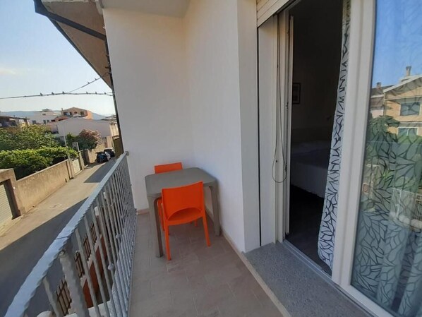 A balcony with a table and chairs, a sliding door, and a view of the neighborhood. - B&b Eden Ogliastra  (Tortolì)