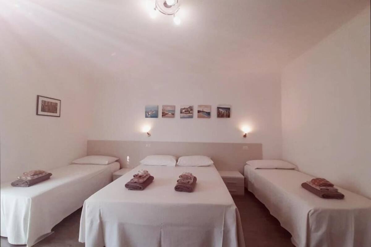 Une chambre d’hôtel avec trois lits simples, un grand lit et une petite table.