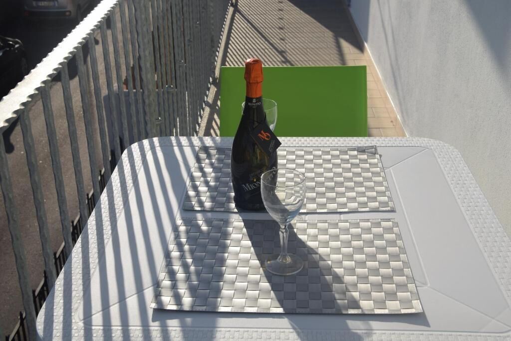 A bottle of wine and a glass on a checkered table mat.