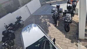 A parking area with multiple motorcycles and a white car. - B&b Eden Ogliastra  (Tortolì)