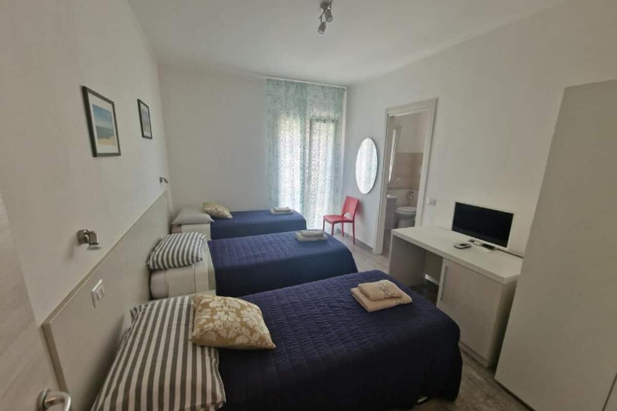 Une chambre avec deux lits, un bureau, une télévision et une chaise.